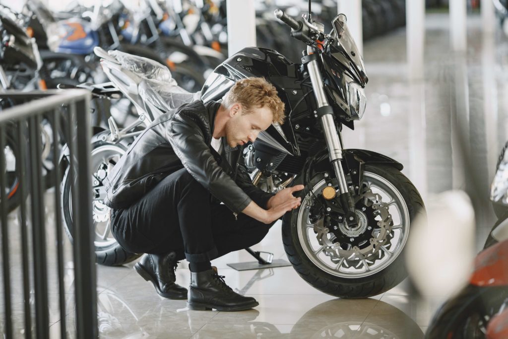man examines the wheel of a new motorcycle