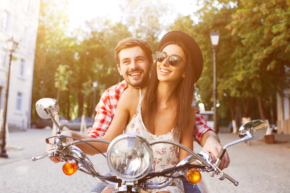 a young couple rides a motorcycle through the city streets